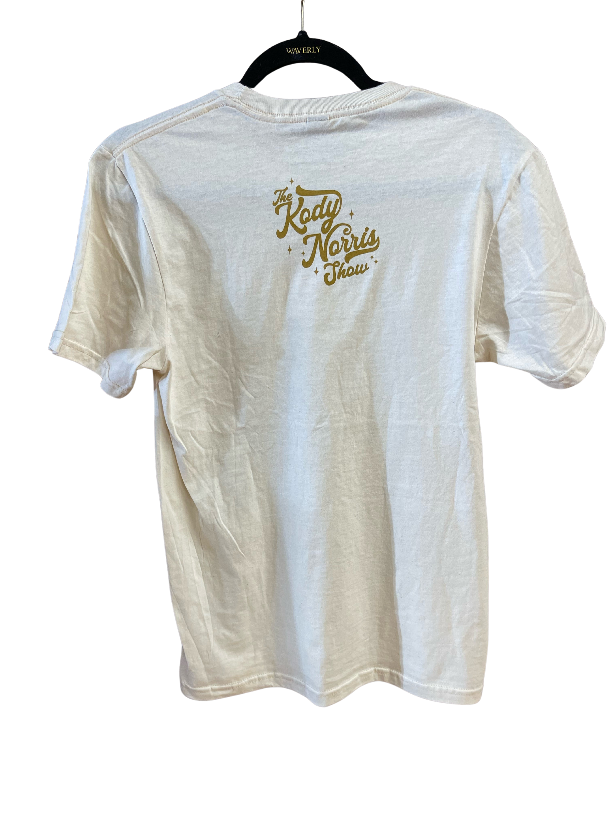 The Kody Norris Show Graphic Tee (Short Sleeve, Color Natural) Gildan Softstyle Tee. Available in Natural with Gold Lettering All Shirts include a secondary logo on the back collar.