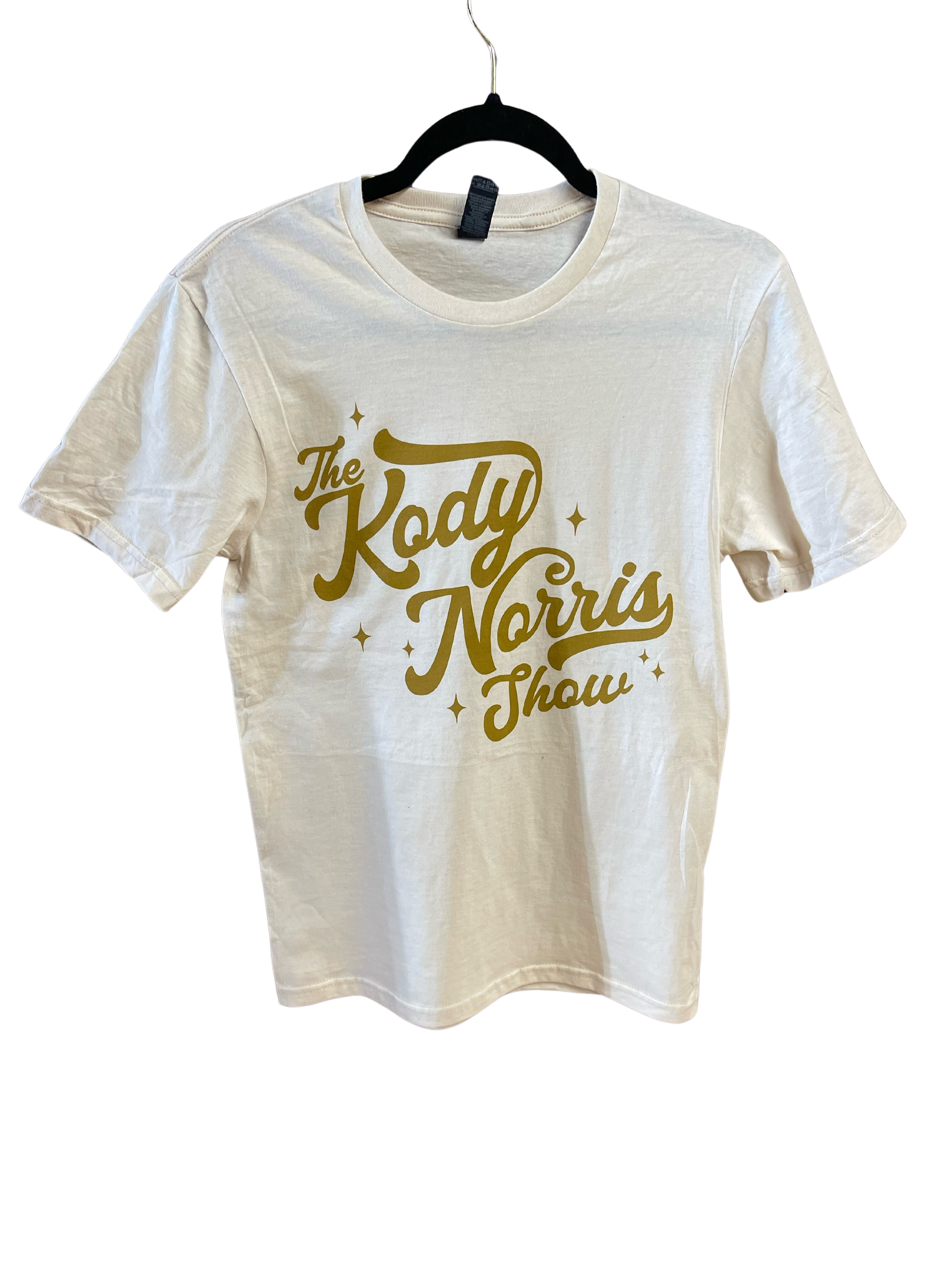 The Kody Norris Show Graphic Tee (Short Sleeve, Color Natural) Gildan Softstyle Tee.   Available in Natural with Gold Lettering   All Shirts include a secondary logo on the back collar.